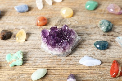 Photo of Aura. Different natural mineral stones on wooden table, closeup