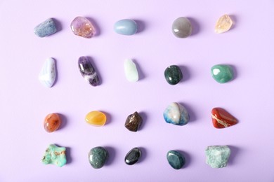 Photo of Aura. Different natural mineral stones on violet background, flat lay