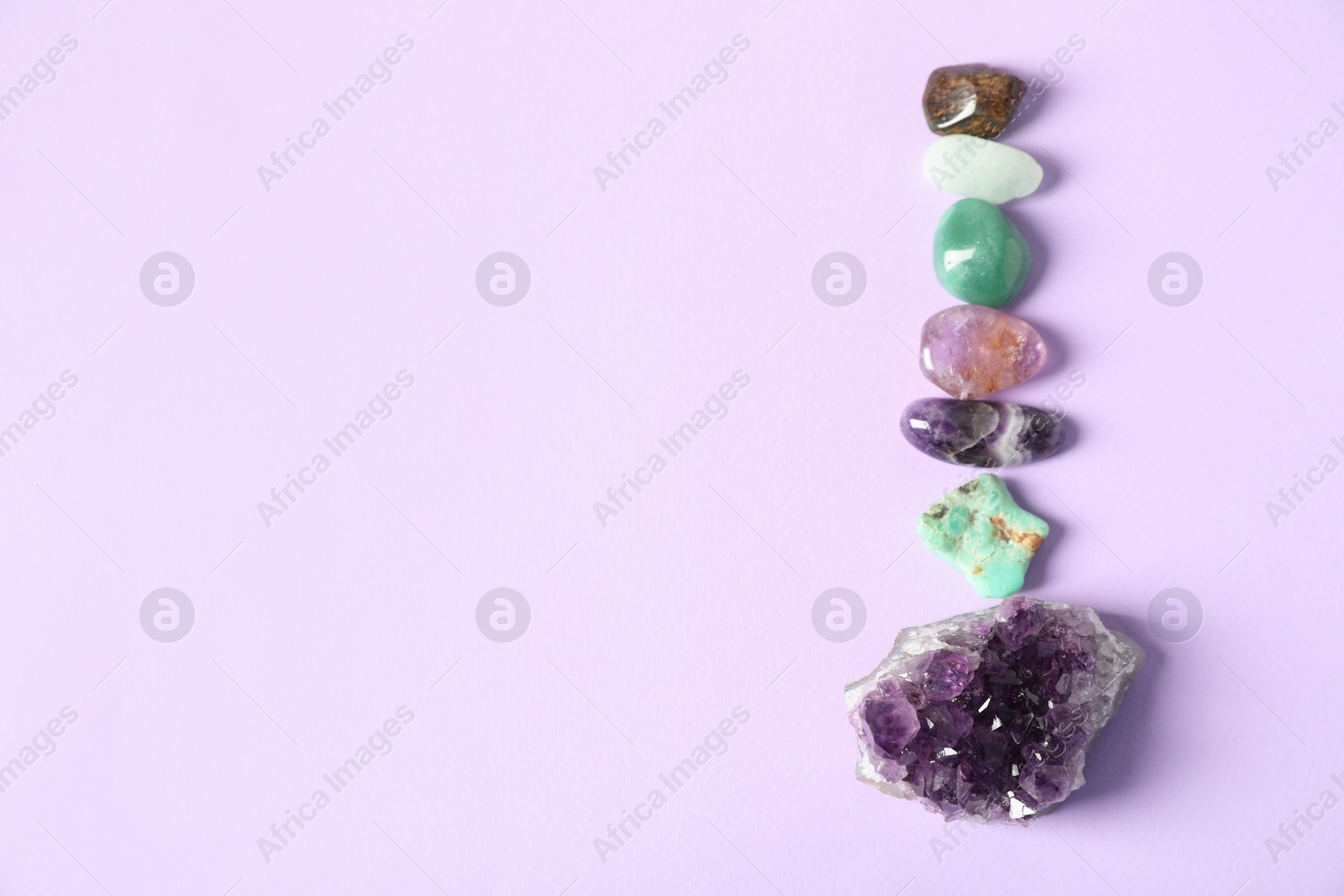 Photo of Aura. Different natural mineral stones on violet background, flat lay. Space for text