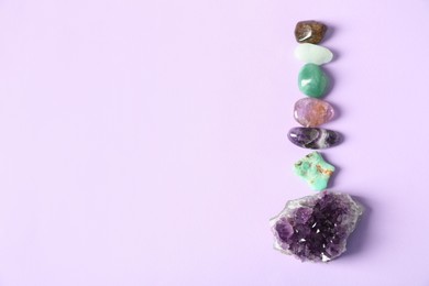 Photo of Aura. Different natural mineral stones on violet background, flat lay. Space for text