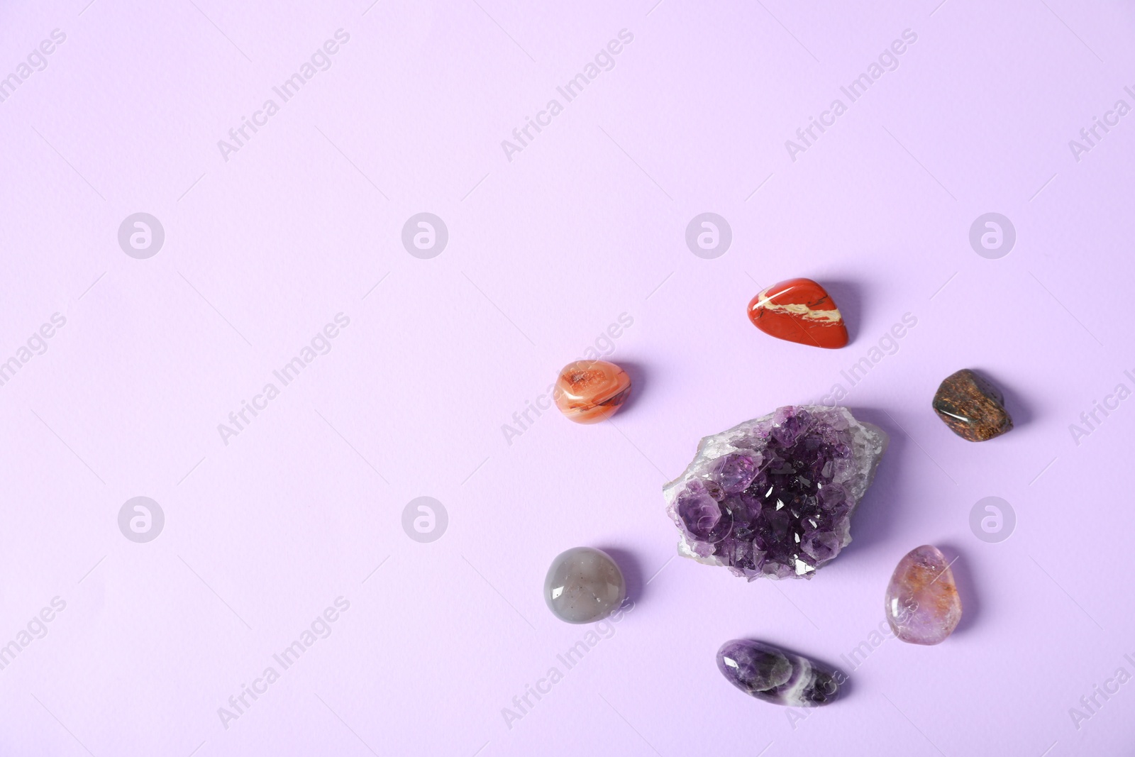 Photo of Aura. Different natural mineral stones on violet background, flat lay. Space for text