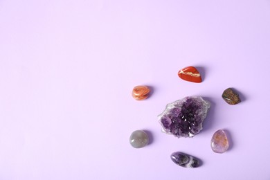 Photo of Aura. Different natural mineral stones on violet background, flat lay. Space for text