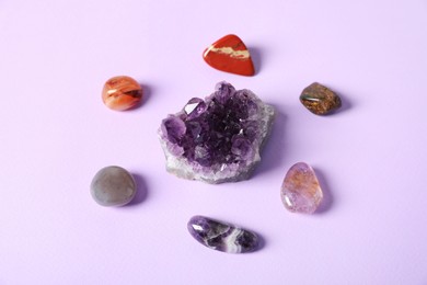 Photo of Aura. Different natural mineral stones on violet background, above view