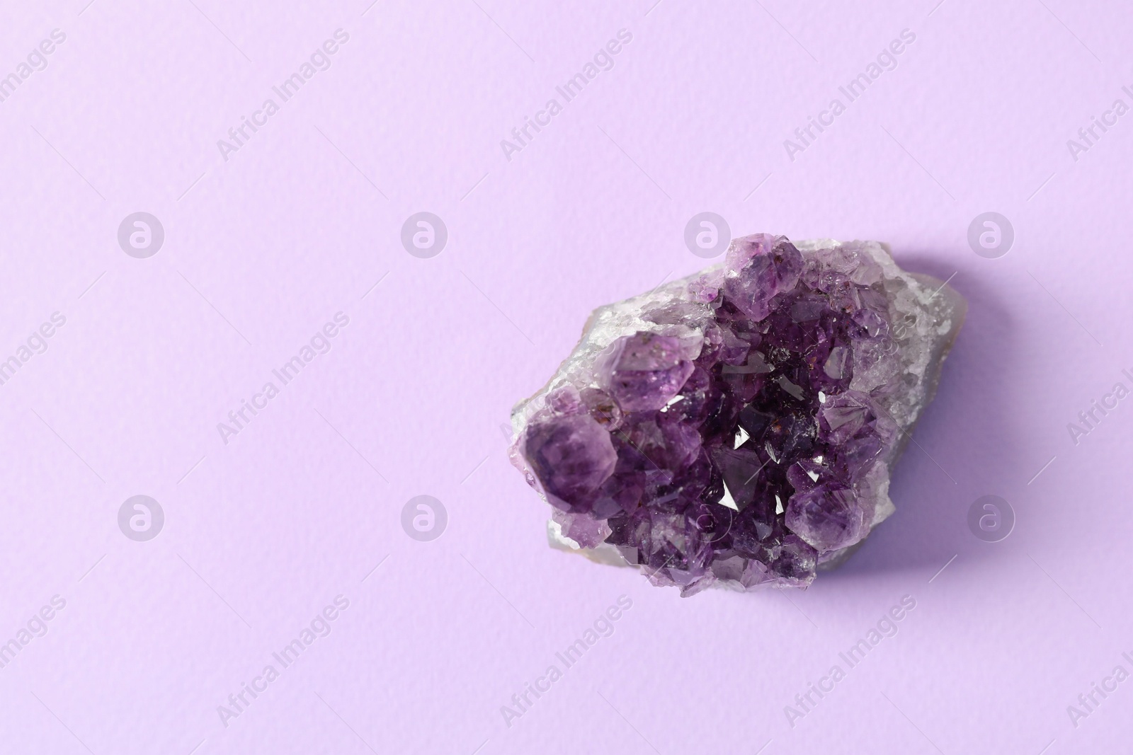 Photo of Aura. One beautiful amethyst on violet background, top view. Space for text