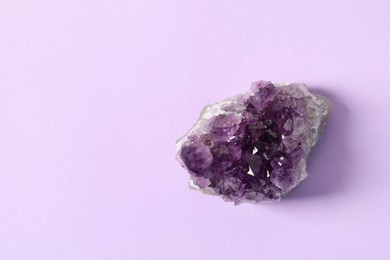 Photo of Aura. One beautiful amethyst on violet background, top view. Space for text