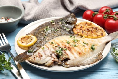 Photo of Tasty roasted flounder fish with herbs and lemon slices served on light blue wooden table, closeup. Homemade seafood dish