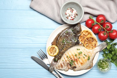 Photo of Homemade seafood dish. Tasty roasted flounder fish with herbs and lemon slices served on light blue wooden table, flat lay. Space for text