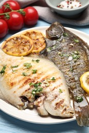 Photo of Tasty roasted flounder fish with herbs, lemon slices and tomatoes on light blue wooden table, closeup. Homemade seafood dish