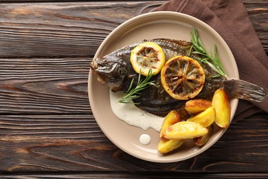 Photo of Homemade seafood dish. Tasty roasted flounder fish with rosemary, potato and lemon slices on wooden table, top view. Space for text