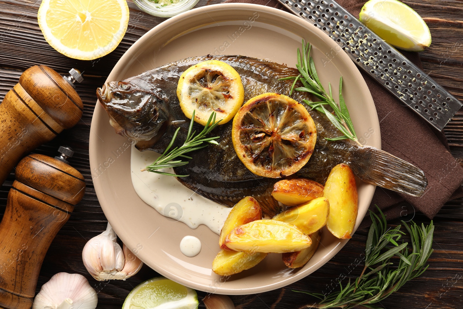 Photo of Tasty roasted flounder fish with rosemary, potato and lemon slices on wooden table, flat lay. Homemade seafood dish