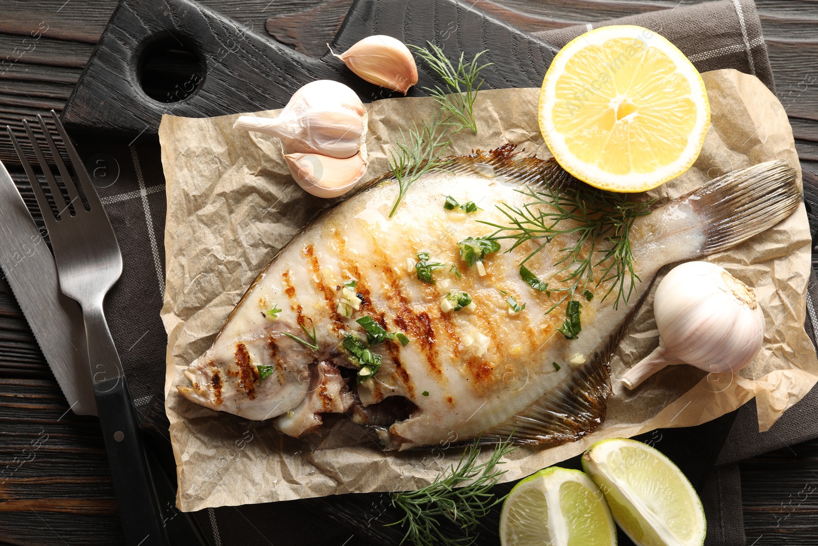Photo of Tasty roasted flounder fish with spices served on wooden table, flat lay. Homemade seafood dish