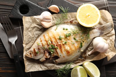 Photo of Tasty roasted flounder fish with spices served on wooden table, flat lay. Homemade seafood dish