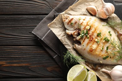 Photo of Homemade seafood dish. Tasty roasted flounder fish with spices on wooden table, top view. Space for text