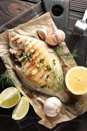Photo of Tasty roasted flounder fish with spices served on wooden table, flat lay. Homemade seafood dish