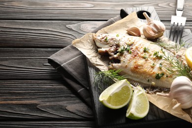 Photo of Homemade seafood dish. Tasty roasted flounder fish with spices served on wooden table, closeup. Space for text