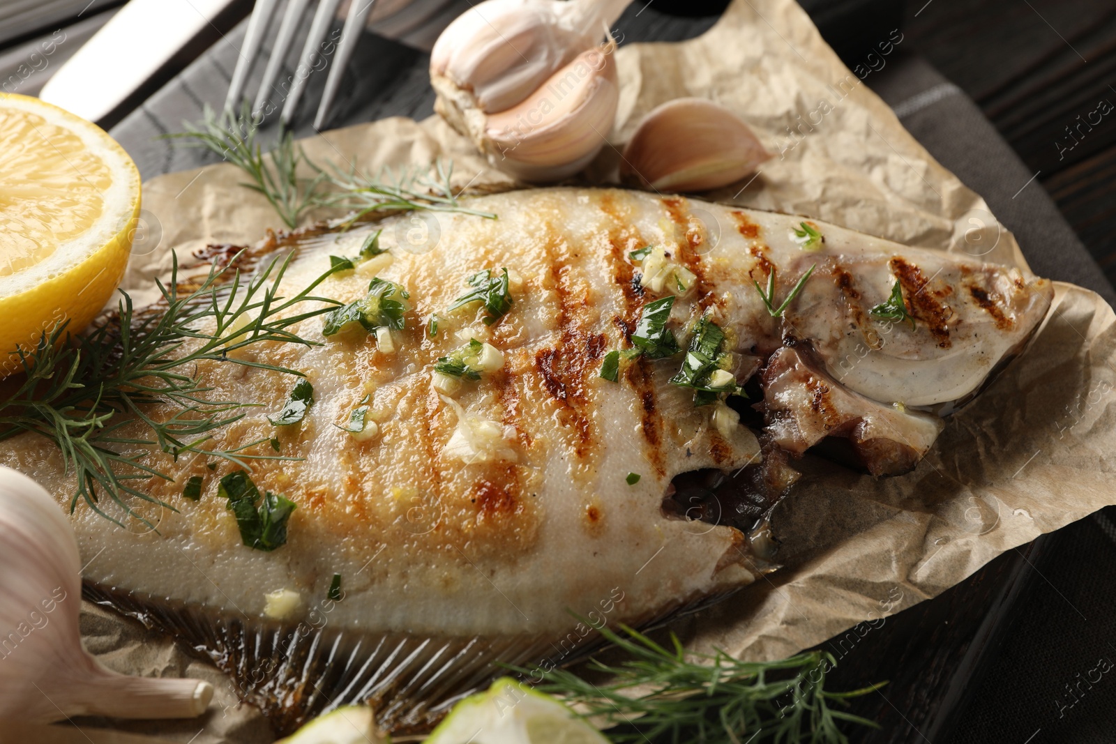 Photo of Tasty roasted flounder fish with spices served on wooden table, closeup. Homemade seafood dish