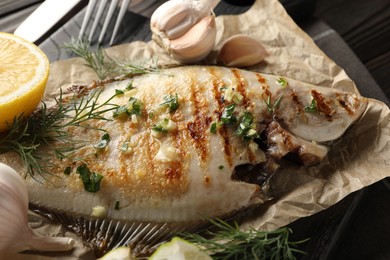 Photo of Tasty roasted flounder fish with spices served on wooden table, closeup. Homemade seafood dish