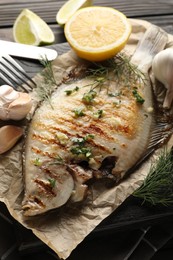 Photo of Tasty roasted flounder fish with spices served on wooden table, closeup. Homemade seafood dish
