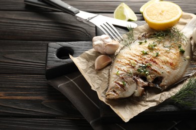 Photo of Tasty roasted flounder fish with spices served on wooden table, closeup. Homemade seafood dish