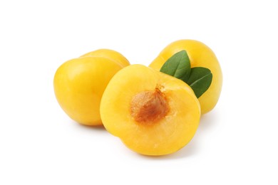 Photo of Whole and cut yellow cherry plums with leaves isolated on white