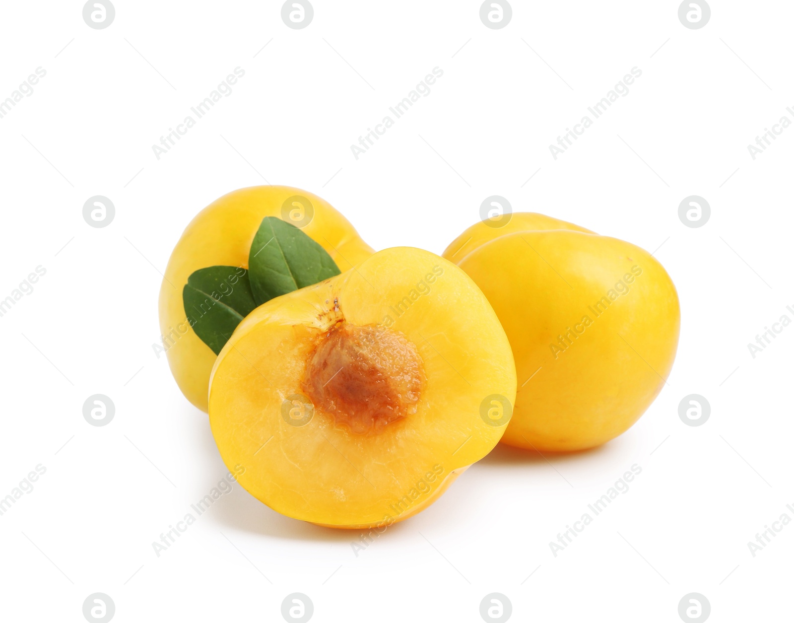 Whole and cut yellow cherry plums with leaves isolated on white Photo of Whole and cut yellow cherry plums with leaves isolated on white