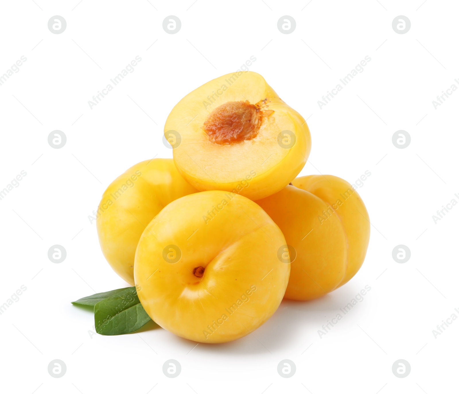 Whole and cut yellow cherry plums with leaves isolated on white Photo of Whole and cut yellow cherry plums with leaves isolated on white