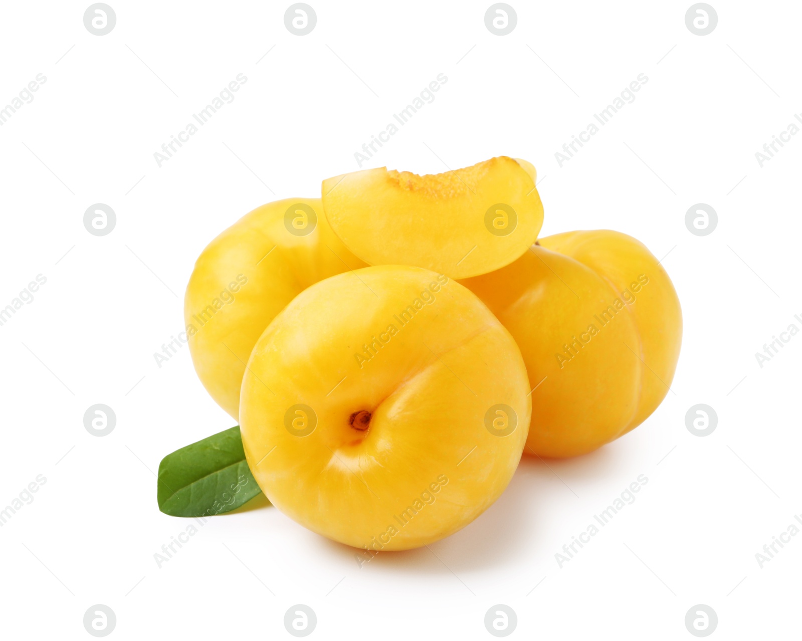 Whole and cut yellow cherry plums with leaf isolated on white Photo of Whole and cut yellow cherry plums with leaf isolated on white