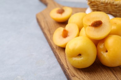 Photo of Ripe yellow cherry plums on grey table, closeup. Space for text