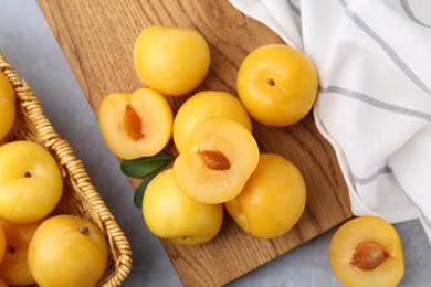 Photo of Ripe yellow cherry plums on grey table, flat lay