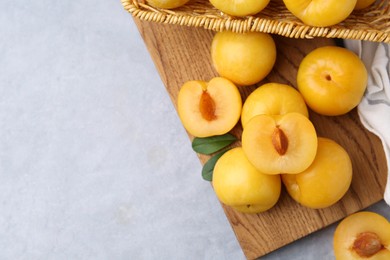 Photo of Ripe yellow cherry plums on grey table, flat lay. Space for text