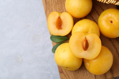 Photo of Ripe yellow cherry plums on grey table, closeup. Space for text