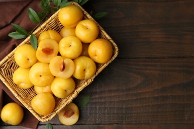Photo of Ripe yellow cherry plums on wooden table, flat lay. Space for text
