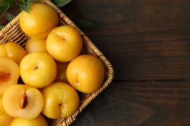Photo of Ripe yellow cherry plums on wooden table, flat lay. Space for text