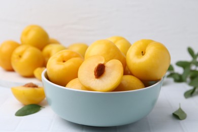 Photo of Ripe yellow cherry plums on white tiled table, closeup