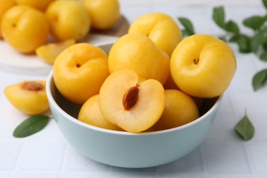 Photo of Ripe yellow cherry plums on white tiled table, closeup