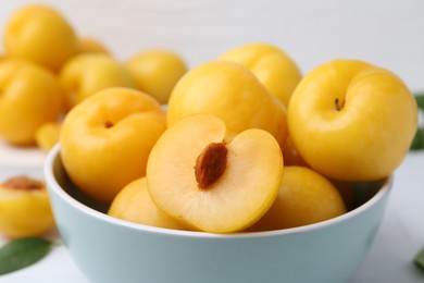 Photo of Ripe yellow cherry plums on white tiled table, closeup