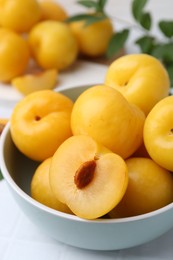 Photo of Ripe yellow cherry plums on white tiled table, closeup