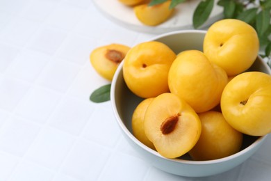 Photo of Ripe yellow cherry plums on white tiled table, closeup. Space for text