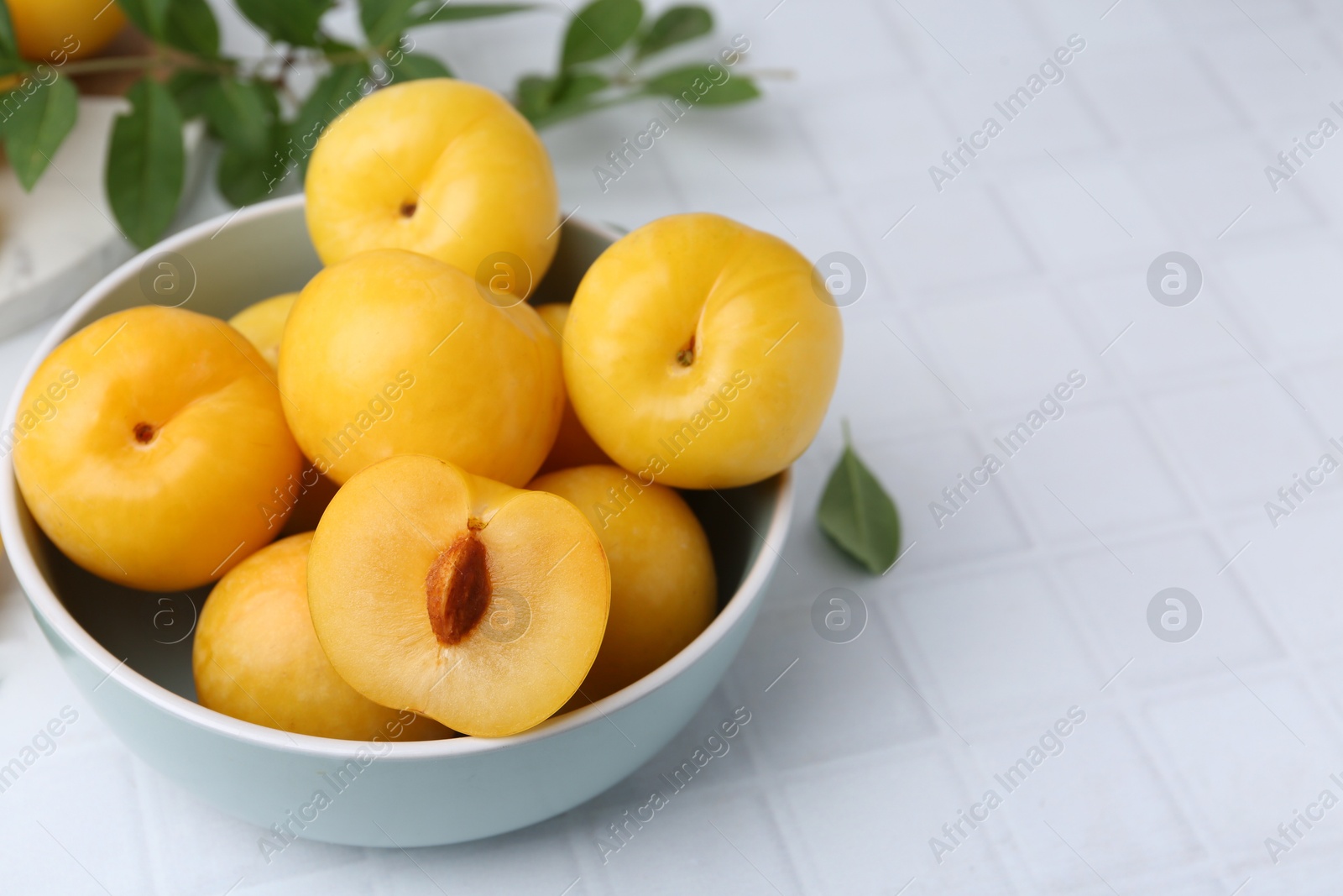 Ripe yellow cherry plums on white tiled table, closeup. Space for text Photo of Ripe yellow cherry plums on white tiled table, closeup. Space for text