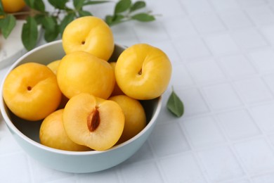 Photo of Ripe yellow cherry plums on white tiled table, closeup. Space for text