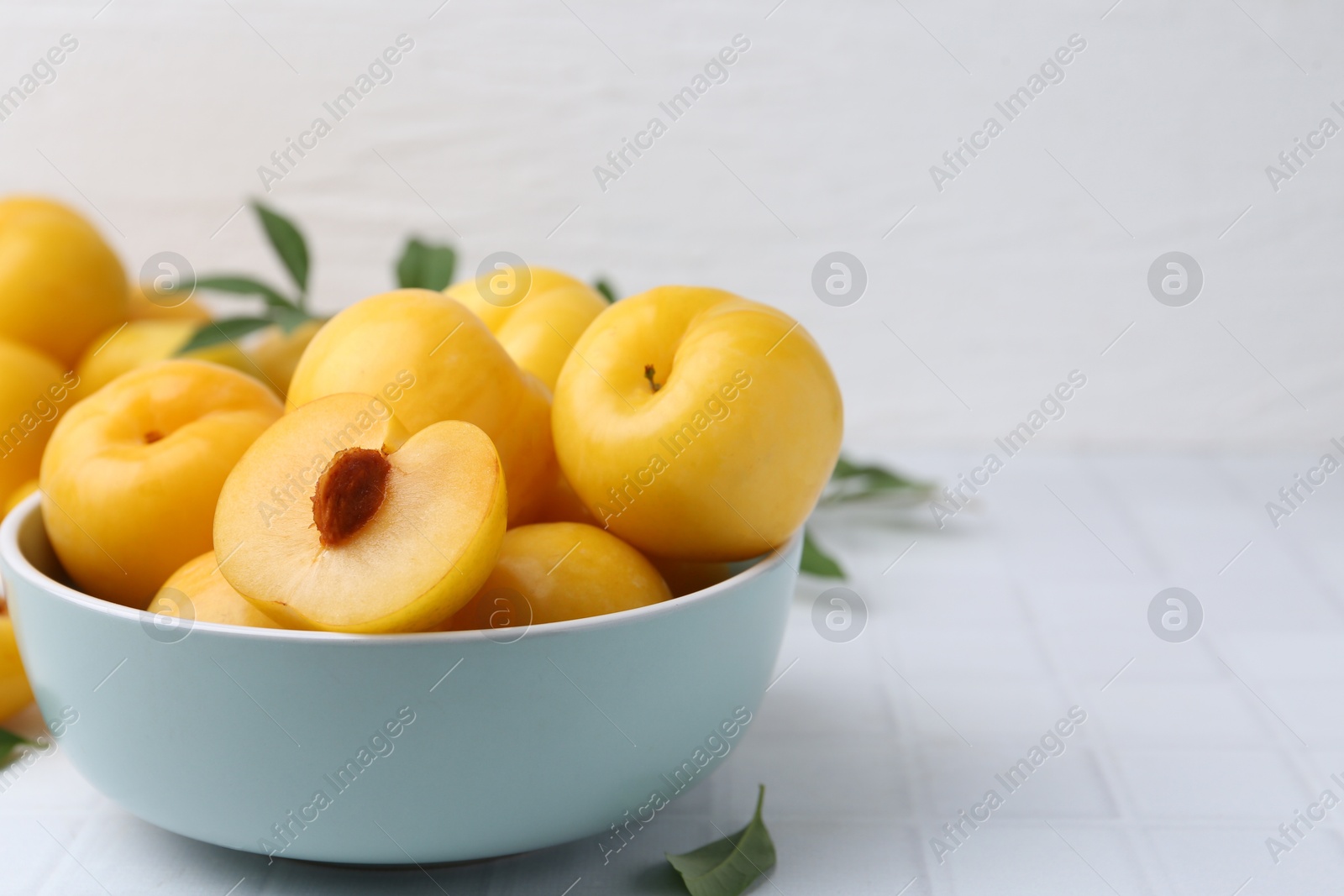 Ripe yellow cherry plums on white tiled table, closeup. Space for text Photo of Ripe yellow cherry plums on white tiled table, closeup. Space for text