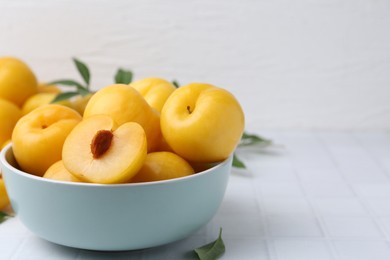 Photo of Ripe yellow cherry plums on white tiled table, closeup. Space for text