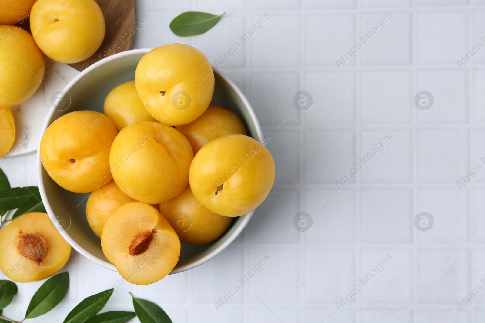 Ripe yellow cherry plums on white tiled table, flat lay. Space for text Photo of Ripe yellow cherry plums on white tiled table, flat lay. Space for text
