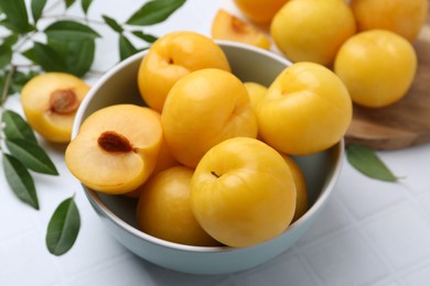 Photo of Ripe yellow cherry plums on white tiled table, closeup