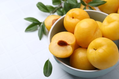 Photo of Ripe yellow cherry plums on white tiled table, closeup