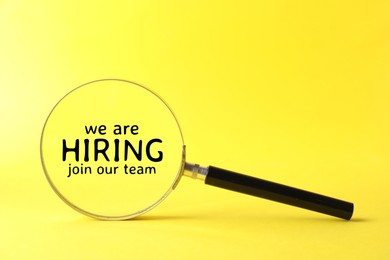 Image of We are hiring, join our team. Magnifying glass with inscription inside on yellow background