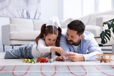 Image of Father and daughter playing on warm floor at home, double exposure with underfloor heating system