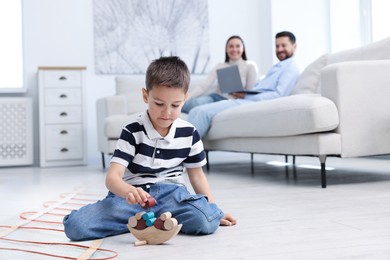 Image of Boy playing on warm floor and his parents on sofa at home, double exposure with underfloor heating system