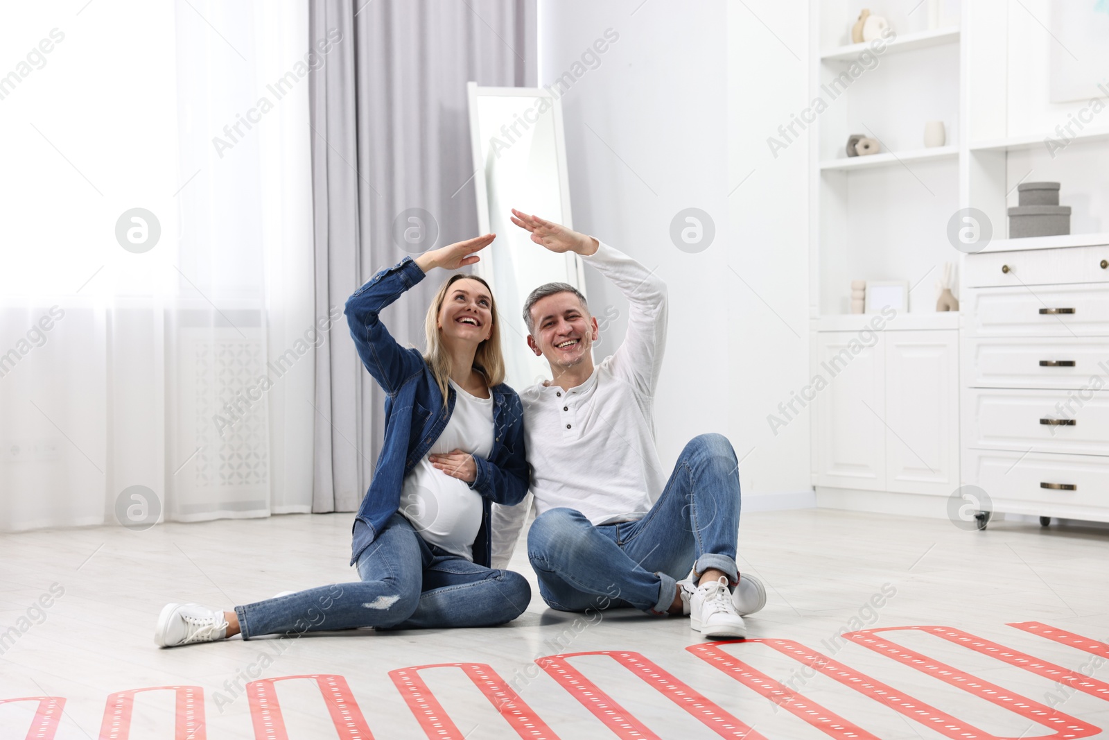 Pregnant woman and her husband on warm floor at home, double exposure with underfloor heating system Image of Pregnant woman and her husband on warm floor at home, double exposure with underfloor heating system