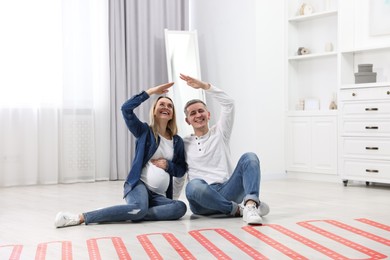 Image of Pregnant woman and her husband on warm floor at home, double exposure with underfloor heating system